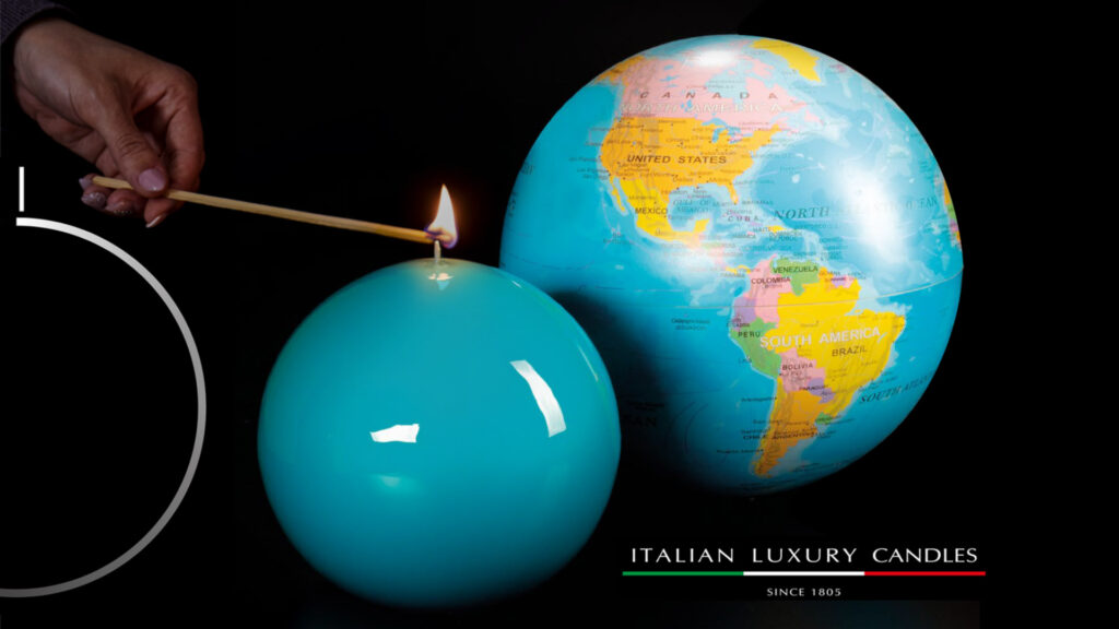 Candela luxury turchese  a sfera con mano che l'accende con un fiammifero e mappamondo sullo sfondo